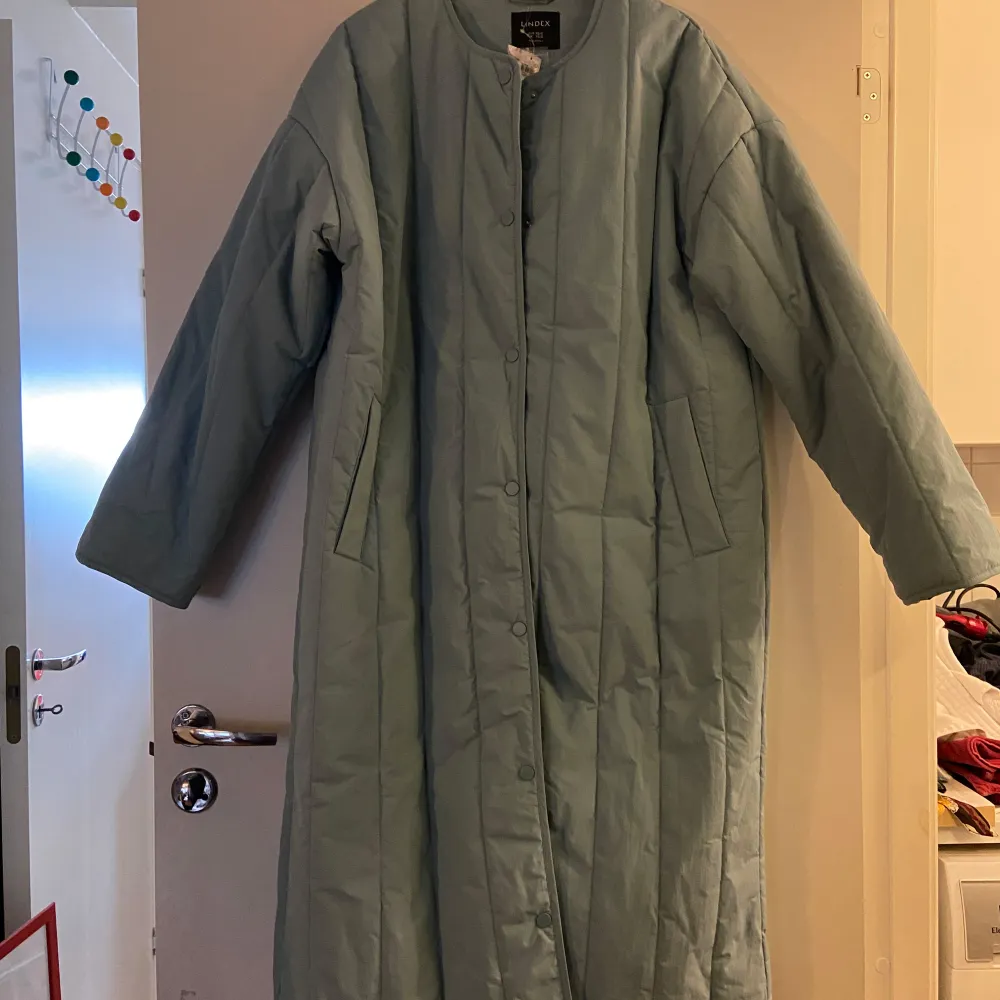 Säljer en superfin turkos/öjusblå quiltad kappa från Lindex i storlek XS/S. Perfekt för höst och vår med sin långa design och knäppning framtill. Den har en stilren look utan krage och är i mycket bra skick. Passar perfekt för dig som vill ha en stilren och bekväm jacka! Oversize-modell som tyvärr blev alldeles för stor på mig som är superliten. Den är så himla fin. Färgen är ljuvlig vilket kanske inte helt framkommer av bilderna. . Takit.