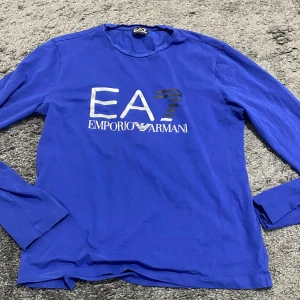 Blå långärmad tröja från Emporio Armani - Säljer en snygg blå långärmad tröja från Emporio Armani. Den har en stor logga på framsidan och är perfekt för en casual look. Tröjan är i bra skick och passar perfekt till både jeans och kostymbyxor. Perfekt för höst och vår! Alla kan bära den💙💙/ köpt på Zalando 
