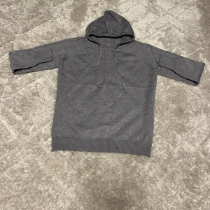 Stickad hoodie  - Säljer en stilren grå stickad hoodie i mycket bra skick. Den har en bekväm passform med ribbade muddar vid ärmslut och nederkant. Perfekt för både höst, vinter och vår. Huvan har snören för justering. Tröjan är oanvänd. Hör av dig vid frågor.
