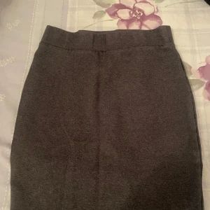 Grå kjol - Snygg grå kjol i klassisk stil. Perfekt för både vardag och kontor. Den har en enkel design utan mönster eller detaljer, vilket gör den lätt att matcha med olika toppar och accessoarer.