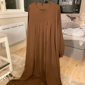 Brun abaya - Ny brun abaya i glansigt tyg med en liten dragkedja fram. Superfin och perfekt året runt. 