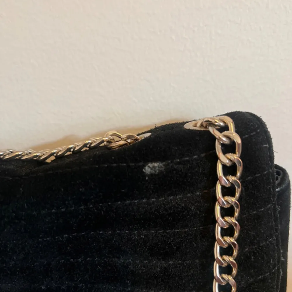 Snygg svart axelväska med en elegant kedja som axelrem. Väskan har en rund metallknapp på framsidan som ger en stilren look. Perfekt för både vardag och fest Finns en liten fläck på den men jag ska prova få bort den innan väskan skickas.. Laukut & Käsilaukut.