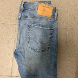 Ljusblå skinny jeans från Jack & Jones - Säljer ett par ljusblå skinny jeans från Jack & Jones i modellen Liam. De är i bra skick och perfekta för både vardag och fest. Klassisk femficksdesign med en snygg tvättad look. Passar perfekt till en casual outfit eller en mer uppklädd stil.