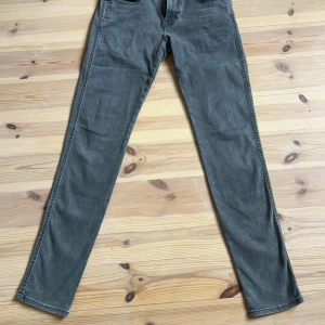 Grå Replay Anbass  - Säljer ett par snygga grå Anbass från Replay i storlek 28. De har en slim passform och är perfekta för både vardag och fest. Jeansen är i bra skick och har en klassisk design med fem fickor och knappgylf. Perfekta för höst och vår!