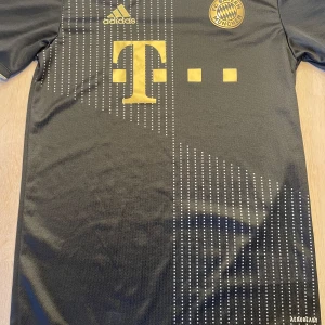 Stilren Bayern München fotbollströja (2021-2022 borta) - Säljer en stilren svart och guldig Bayern tröja. Kan användas som en vanlig tröja eller träningströja. Finns plats att trycka valfrit spelar namn och nummer. Tröjan är lätt att matcha med outfits. Pris kan förhandlas!