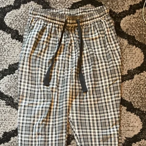 Rutig mjukisbyxa med snörning - Säljer ett par superbekväma mjukisbyxor i svartvitt rutigt mönster. De har en elastisk midja med snörning för perfekt passform. 