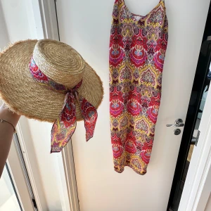 Klänning och hatt - Letar du efter det ultimata statement-plagget för ditt nästa evenemang? Sök inte längre! Vår ärmlösa, rygglösa festklänning utstrålar elegans och sofistikering. Med sin eleganta design och smickrande silhuett är denna klänning perfekt för att göra en