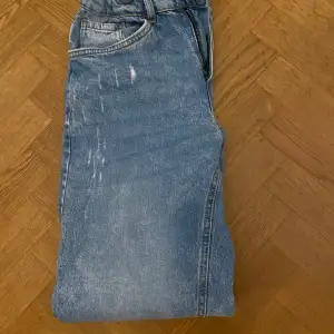 Säljer ett par klassiska blå jeans från Lindex i storlek 13-14y / 164. De har en straight passform och är perfekta för vardagsbruk. Jeansen är i bra skick och har en snygg ljusblå tvätt. 