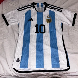 Argentina 2022 Messi - Hej! Jag säljer en argentina tröja från året de vann VM med Messi, 2022. Med messi på baksidan. Helt ny med tag. Säljer för 400. Skriv om frågor. Spelarversion.
