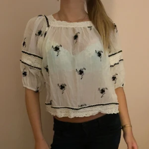 Vit blus med broderade blommor - Säljer en superfin vit blus med svarta broderade blommor. Den har trekvartsärmar och är handbroderad från Italien även köpt där, går inte att få tag på💖💖❤️