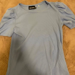 Ribbad, babyblå tshirt med puffärmar  - Ribbad, baby blå tshirt med puffärmar vid axlarna. Tycker själv det är en väldigt fin topp men den sitter väldigt stort för mig. 