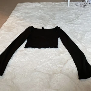 Svart ribbad croppad topp - Säljer en svart ribbad croppad topp med långa ärmar. Perfekt för en stilren och enkel look. Toppen är tight och passar bra till både vardag och fest.