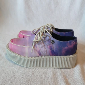 T.U.K. creepers/platåskor - Gulliga pastelliga creepers från T.U.K. i strl. EU 37 som egentligen är som en EU 36 då deras storlekar är ett snäpp mindre än det normala. De köptes utomlands 2015, för ungefär 1300kr, och användes under en 3-4 dagars resa men sen dess stått orörda då de varit för små. Har försökt få med så många bilder som möjligt på skornas tillstånd i dessa 5 bilder, men pm:a ifall du vill ha fler! De har några svaga fläckar på sig som de tyvärr kom med från början vid köpet, annars är de i väldigt gott skick! Stålringarna vid snörningen har över tid lämnat gråa märken på tyget, men dessa märks inte alls när man knyter dem och använder dem som vanligt. Platformsen är inte kritvita utan mer åt det gråa hållet. Dessa creepers har utgått från T.U.K.s sortiment och går därför inte att köpa på hemsidan längre. Har tyvärr ingen T.U.K-skokartong till dem eftersom det var så längesen ***Köpare står för frakt om inget anges :)