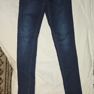 Levi's 711 Skinny Jeans - Snygga Levi's 711 skinny jeans i mörkblå denim. De har en tight passform och klassisk femficksdesign med knapp och dragkedja framtill. Perfekta för en stilren look.