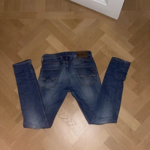 Blå jeans från Replay - Snygga blå jeans från Replay i modellen Anbass. De har en klassisk femficksdesign och en liten slitsdetalj på båda benen. Perfekta för en avslappnad stil med en modern touch. 29/34