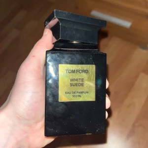 Tom Ford White Suede Eau de Parfum 100 ml - Säljer en elegant Tom Ford White Suede Eau de Parfum i en stilren svart flaska med guldetikett. Flaskan rymmer 100 ml och kommer i sin originalförpackning. Perfekt för den som älskar lyxiga och sofistikerade dofter.100ml