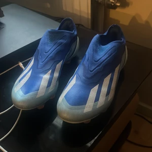 Blå fotbollsskor från Adidas - Snygga blå fotbollsskor från Adidas med vita detaljer och texten 'Crazyfast' på sidan. Skorna har en strömlinjeformad design med dobbar för optimalt grepp på planen.  