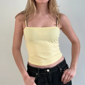 Gul linnetopp - Säljer en söt gul linnetopp med smala axelband. Perfekt för varma sommardagar. Toppen är figurnära och ger en fräsch look.
