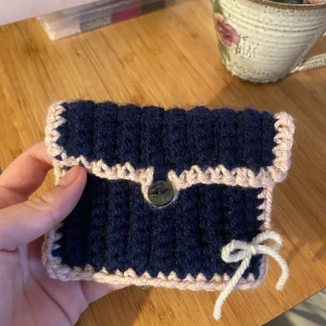 Virkad plånbok - Egentillverkad mörkblå plånbok med ljusrosa kant, vit rosett och förslutande knapp💙9x12cm