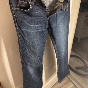 Blå jeans med dragkedja - Snygga blå jeans med klassisk femficksdesign och dragkedja. De har en rak passform och är perfekta för en avslappnad stil. Jeansens slitna look ger dem en trendig touch. 