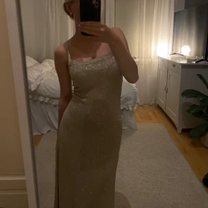 Glittrig guldklänning - Säljer en elegant glittrig guldklänning med smala axelband och en stilren slits. Perfekt för en festlig kväll! ✨den är ganska tunn och kan användas antingen som en klänning eller som en strandklänning. Den har snörning i ryggen och går nästan hela vägen ner till fötterna på mig som är 165 cm lång! Skriv om du är intresserad och jag kan diskutera pris!❤️❤️aldrig använd och köpt i Grekland