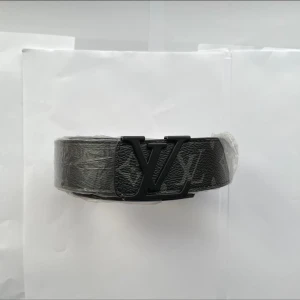 Svart bälte med monogramspänne - Snyggt svart bälte med ett stilrent monogramspänne. Perfekt för att ge en lyxig touch till din outfit. Tillverkat i ett elegant material som ger en exklusiv känsla.