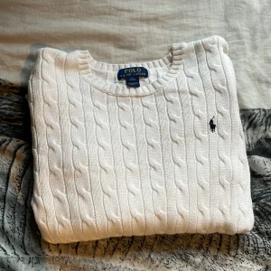 Vit kabelstickad tröja från Ralph Lauren - Ordinarie pris 1300kr. Säljer en klassisk vit kabelstickad tröja från Ralph Lauren. Tröjan har en rund halsringning och det ikoniska logotypbroderiet på bröstet. Väldigt god skick och otroligt fint material. Storlek 14-16 år men jag är Dam S och passar jättebra.