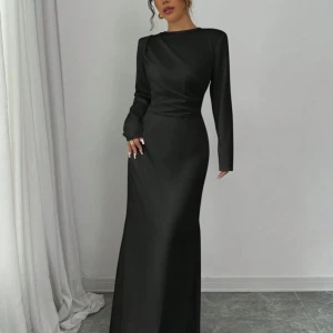 Svart långklänning - Elegant svart långklänning med långärmad design och en figurnära passform. Klänningen har en stilren och tidlös look, perfekt för formella tillfällen.