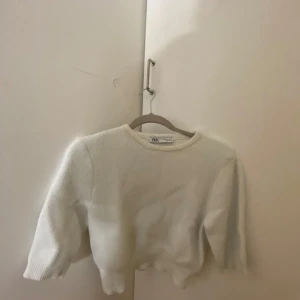 Vit croppad tröja från Zara - Säljer en vit croppad tröja från Zara. Tröjan har en mjuk och fluffig textur med trekvartsärmar. Perfekt för en stilren och bekväm look. Passar bra till både jeans och kjol. 🖤hör av er vid minsta fråga!!!