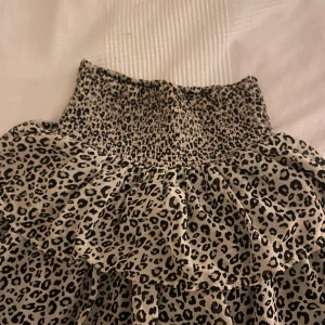 Leopardmönstrad kjol med volang - Trendig leopardmönstrad kjol med volangdetaljer och en elastisk midja för bekväm passform. Perfekt för att ge din outfit en djärv touch. (Kan användas som volang tubtopp oxå!!)
