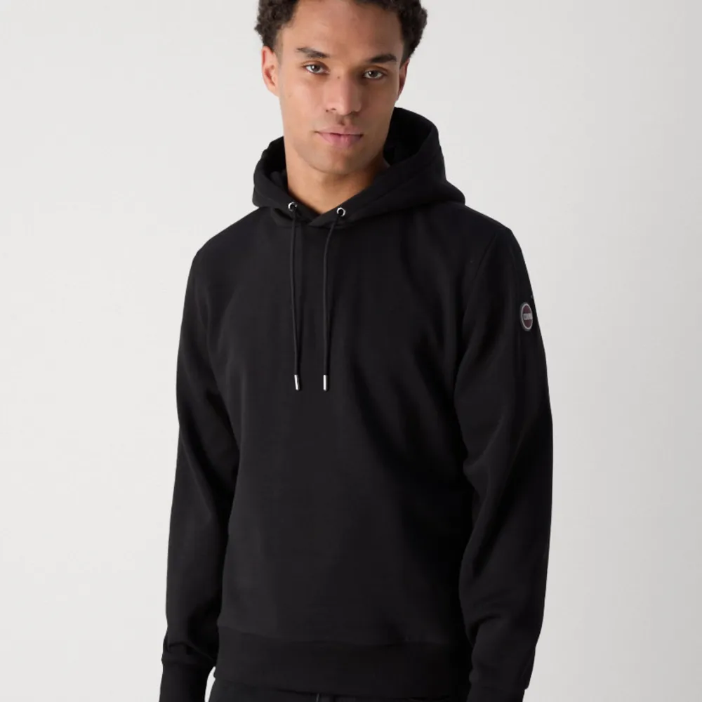 Säljer en stilren svart hoodie från Colmar med justerbar huva och logotyp på ärmen. Perfekt för en avslappnad look. Passar bra till både jeans och träningsbyxor. Storlek S sitter som S/XS. Neuletakit & Villapaidat.