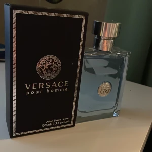 Versace Pour Homme After Shave Lotion - Säljer en Versace Pour Homme After Shave  i en elegant glasflaska med silverfärgad kork. Flaskan rymmer 100 ml och har en stilren design med Versaces ikoniska logotyp i silver på framsidan. Perfekt för den som vill ha en fräsch och maskulin doft efter rakning. Den är helt ny och är helt full med 100 ml av god doftande parfym.