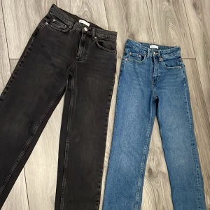 Svarta och blå jeans från Ginatricot  - Två par jeans från Ginatricot i storlek 32. Ett par är klassiskt svarta och det andra är blå. Båda har en straight passform med femficksdesign och knappgylf. Perfekta för en stilren look. Blå använda 1 gång svarta aldrig använda. Nyligen köpta. 