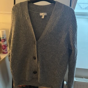 grå cardigan  - Grå cardigan från h&m. Inte mycket använd men är lite nopprig.