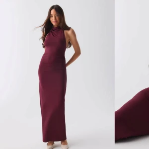 Vinröd långklänning - Elegant vinröd långklänning med halterneck-design. Klänningen har en tight passform som framhäver figuren och är perfekt för festliga tillfällen. Den är ärmlös och tillverkad i ett mjukt material som ger en lyxig känsla.