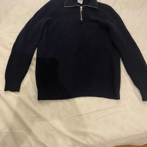 Svart ribbad tröja med dragkedja från zara - Säljer en stilren mörkblå ribbad tröja med dragkedja vid halsen. Perfekt för kyligare dagar och passar till det mesta i garderoben. Tröjan har långa ärmar och en klassisk look.