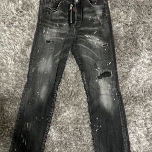 Svarta jeans med slitningar - Coola svarta jeans med slitningar och en unik tvättad look. De har en klassisk femficksdesign och en knappgylf. Perfekta för en avslappnad stil med en edgy touch.