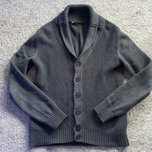 Mörkgrå kofta - Säljer nu en stilren mörkgrå kofta från WE. Den har en djup v-ringning och knappar framtill. Koftan är ribbad vid krage, ärmslut och nederkant vilket ger en snygg passform. Perfekt för kyligare dagar. Modellen är 185 Skick 10/10 nästan helt ny. Ny pris 849 mitt pris 549. Priset är ej hugget i sten så kom med bud.