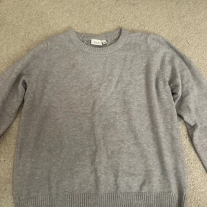 Grå tröja från VILA - Säljer en stilren grå tröja från VILA i storlek XL. Tröjan är långärmad och har en ribbad rund halsringning samt ribbade muddar vid ärmslut och nederkant. Perfekt för kyligare dagar.