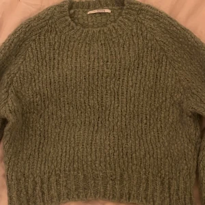 Grön stickad tröja  - Mysig grön stickad tröja från sibin linnebjerg med en grovstickad design. Perfekt för kyliga dagar med sin avslappnade passform och långa ärmar. Enkelt att matcha med dina favoritjeans eller kjol.