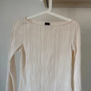 Vit ribbad långärmad topp gina tricot - Säljer en stilren vit ribbad topp med långa ärmar. Perfekt för lager-på-lager eller som den är. Enkel och elegant design som passar till många tillfällen.