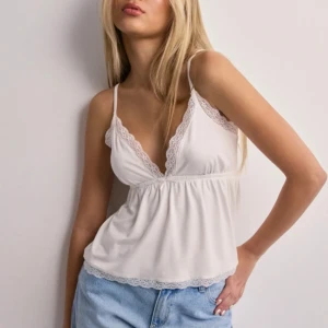 Vit spetsdetaljerad linnetopp - Säljer en söt vit linnetopp med smala axelband och spetsdetaljer, då den aldrig kommit till användning därav nyskick! Passar perfekt till festtillfällen🥰(Köparen står för frakten om det krävs🫶🏻)