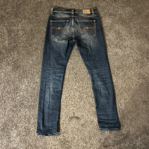 BlåaNudie Jeans lean dean - Säljer ett par snygga blå jeans från Nudie Jeans. De har en klassisk femficksdesign med orange sömmar och en bekväm passform. Perfekta för en avslappnad stil. Storlek 31/32