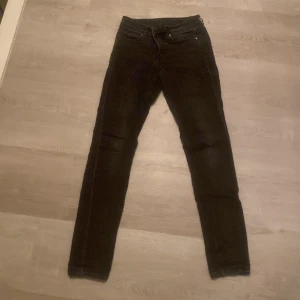 Svarta jeans från H&M Divided - Snygga svarta jeans från H&M Divided i storlek XS. De har en tight passform och är perfekta för en stilren look. Klassisk design med svarta byxor och knappgylf.