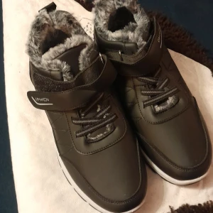 Svarta vinterkängor med fuskpäls - Snygga svarta kängor från Echox med fuskpälsfoder och snörning. De har en robust sula med rött mönster för extra grepp. Perfekta för kalla vinterdagar.