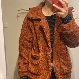 Teddyjacka - Mysig brun teddyjacka med dragkedja och stora fickor. Perfekt för vinter eller höst. Märket är oklart, köpt i USA, finns inga tecken på slitage, 