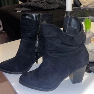 Svarta mocka boots med dragkedja - Snygga svarta boots i mocka med dragkedja på sidan och en stabil klack. Perfekta för både vardag och festliga tillfällen.