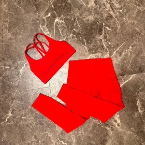 Lululemon - rött set - Rött Lululemon set, tights + bh. Endast anänd 1 gảng för ett jobb. Bada i storlek 6. Tightsen är i ankellängd. Jag tycker att bhin och tightsen har en liten nyans skillnad, men det ar inget som uppfattas varken pa bild eller när deär pa! :)