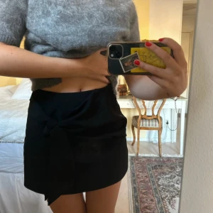 Kjol - Svart shorts-kjol från Zara med knytning på sidan (man kan göra en rosett också). Storlek XS. Dragkedja baktill. Medelhög midja. Så snygg passform! Jättebra skick.🖤🖤🖤