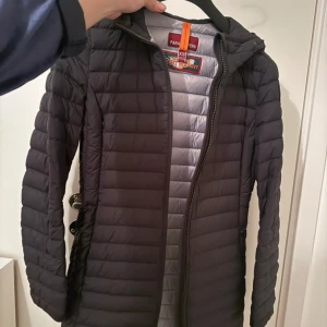 Parajumpers dunjacka - Säljer en stilren svart dunjacka från Parajumpers i storlek XS. Jackan har en praktisk huva och dragkedja framtill. Perfekt för kyliga dagar med sin lätta och värmande design.
